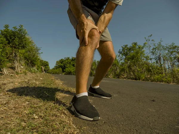 Närbild händer och ben sport man skadad vidröra knät i smärta lider fysiska problem eller någon skada under löpning träning utomhus i sjukvården koncept — Stockfoto