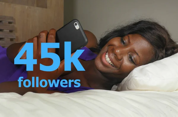 Mujer afroamericana negra feliz acostada relajada en la cama usando el teléfono móvil de Internet sonriendo red alegre consiguiendo seguidores en los medios sociales en estilo de vida influencer exitoso — Foto de Stock