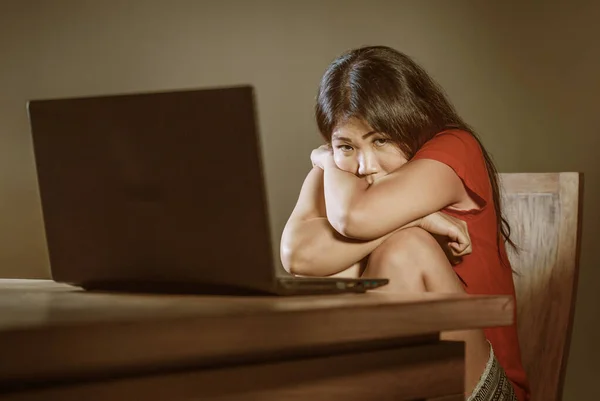 Дівчинка азіатського підлітка знущається в Інтернеті. Пригнічена і налякана молода жінка з комп'ютерним ноутбуком страждає від кіберзнущань, над якими знущаються в Інтернеті сталкери або студенти пліток. — стокове фото