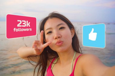 young beautiful and happy influencer Korean woman taking self portrait getting likes and new followers in travel blogger success