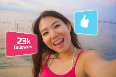 young beautiful and happy influencer Korean woman taking self portrait getting likes and new followers in travel blogger success