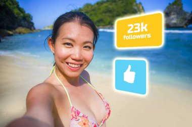 young beautiful and happy influencer Korean woman taking self portrait getting likes and new followers in travel blogger success