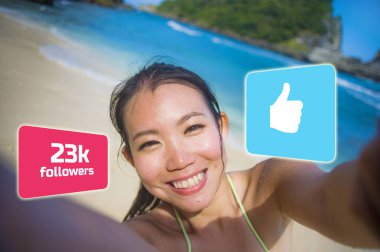 young beautiful and happy influencer Korean woman taking self portrait getting likes and new followers in travel blogger success