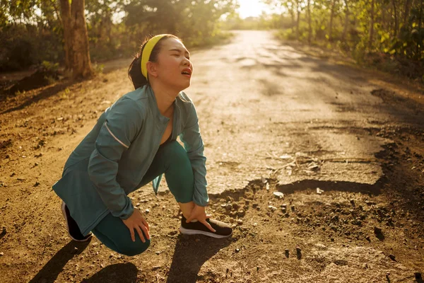 Fitness styl życia portret młodej atrakcyjnej azjatyckiej biegacz koreański kobieta cierpi uraz sportowy podczas joggingu trening na Sunset Road gospodarstwa skręcone kostki w bólu — Zdjęcie stockowe
