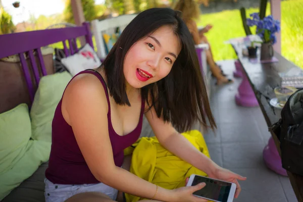 若い美しく幸せなアジア系韓国人女子大生のライフスタイルポートレートインターネットソーシャルメディアアプリネットワーキングで携帯電話屋外でクールなカフェで笑顔陽気に — ストック写真