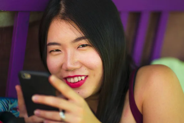 Retrato de estilo de vida de jovem bela e feliz menina estudante asiática chinesa usando internet rede de aplicativos de mídia social com telefone de mão ao ar livre no café legal sorrindo alegre — Fotografia de Stock