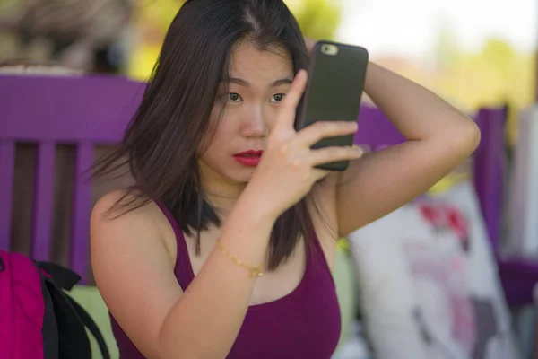 Retrato de estilo de vida natural de jovem bonita e feliz mulher asiática coreana verificando seu cabelo e maquiagem antes de uma data ao ar livre no café usando telefone celular como espelho — Fotografia de Stock