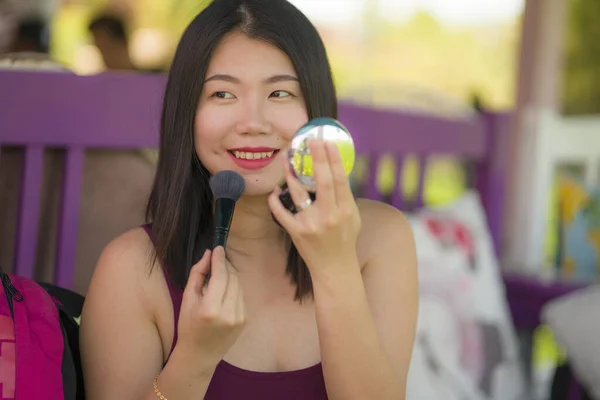 Retrato de estilo de vida natural de jovem bonita e feliz mulher asiática coreana retocando maquiagem antes de uma data ao ar livre no café usando escova e pouco espelho no conceito de beleza — Fotografia de Stock