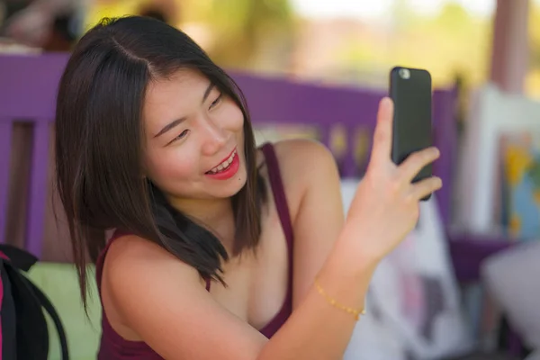 Estilo de vida natural toma de joven hermosa y feliz mujer coreana asiática tomando foto retrato selfie con teléfono de la mano sonriendo sentado al aire libre disfrutando de vacaciones de verano — Foto de Stock