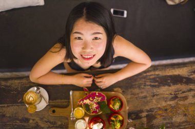 Sebzeli kahvaltı. Genç mutlu ve güzel Asyalı Çinli kadının doğal yaşam tarzı portresi açık havada organik kahvaltı yiyor vejetaryen yemeklerinin serin kafesinde