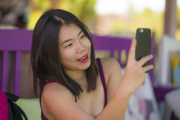 Dulce asiática chica tomando selfie con mano teléfono. joven hermosa y feliz japonesa mujer tomando foto autorretrato sonriente alegre sentado al aire libre disfrutando de verano — Foto de Stock