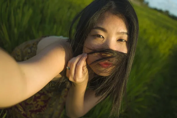 Jong gelukkig en mooi aziatisch vrouw nemen selfie foto buiten. vrolijk Chinees meisje in de zomer jurk nemen zelfportret op groen veld genieten van vakantie — Stockfoto