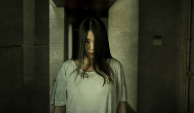 Geceleri karanlık otel koridorunda yabancı bir Asyalı kızın Japon korku filmi tarzı portresi korku ve korkunç Cadılar Bayramı anısına garip ve şüpheli görünüyor.