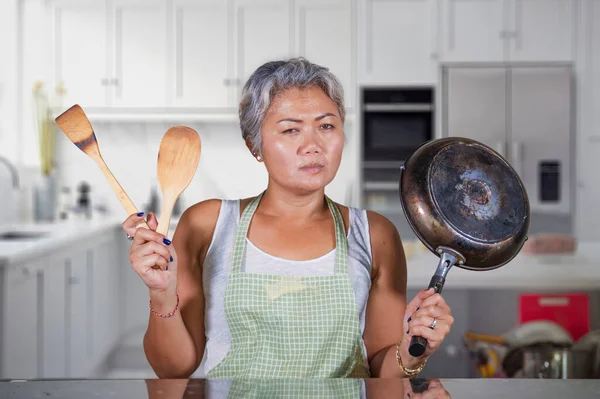 Atrakcyjne zdenerwowany i zestresowany kobieta 40 do 50 lat zmęczony i nieszczęśliwy w domu kuchnia robi prace domowe i nudne prace domowe uczucie sfrustrowany gospodarstwa patelni — Zdjęcie stockowe