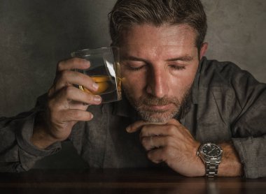 Çekici alkolik adam. Depresyondaki bağımlı viski bardağının önünde izole edilmiş sarhoş ve alkolizm ve alkol bağımlılığı çeken dramatik bir ifadeyle harcanmış.