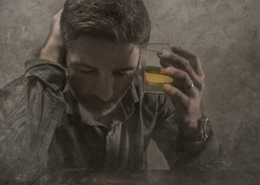 Alkolik ve alkolik bir adam viski bardağının önünde oturmuş dramatik bir ifadeyle içkiye tutunmaya çalışıyor alkolizm ve alkol bağımlılığı çekiyor.