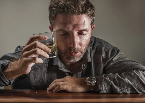 Uomo attraente alcolizzato. depresso tossicodipendente isolato di fronte a bicchiere di whisky ubriaco e sprecato in espressione drammatica che soffre di alcolismo e dipendenza da alcol — Foto Stock