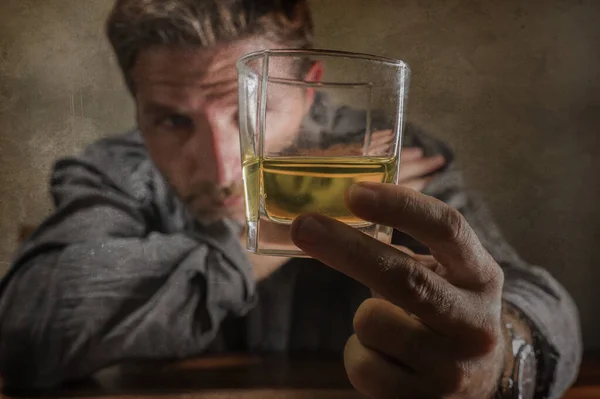 Uomo attraente alcolizzato. depresso tossicodipendente isolato di fronte a bicchiere di whisky ubriaco e sprecato in espressione drammatica che soffre di alcolismo e dipendenza da alcol — Foto Stock