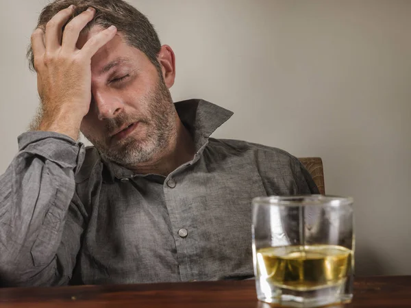 Alcolizzato depresso e ubriaco drogato seduto davanti al bicchiere di whisky cercando di trattenere il bere in espressione drammatica che soffre di alcolismo e dipendenza da alcol — Foto Stock