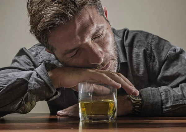 Alcoólico deprimido e bêbado viciado homem sentado na frente de copo de uísque tentando segurar em beber em expressão dramática sofrendo alcoolismo e dependência de álcool — Fotografia de Stock