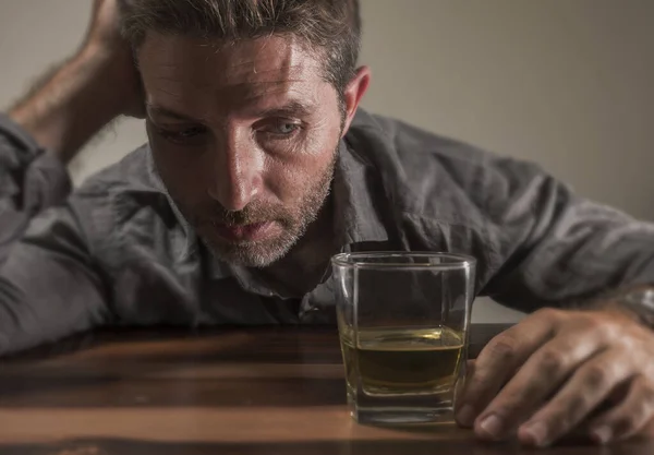 Alcoólico deprimido e bêbado viciado homem sentado na frente de copo de uísque tentando segurar em beber em expressão dramática sofrendo alcoolismo e dependência de álcool — Fotografia de Stock