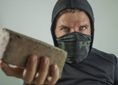 Radikal ve agresif bir anarşist olan genç adam tuğla tutuyor. Yüzü maskeli öfkeli sistem karşıtı protestocu beyazlara izole edilmiş şiddetli ayaklanmalara taş atıyor.