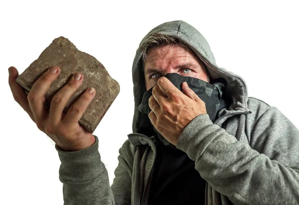 Junger Mann als fanatischer und aggressiver anarchistischer Randalierer. Wütender und beängstigend gewalttätiger Anti-System-Demonstrant mit Gesichtsmaske, der Ziegelsteine wirft und dabei feindselig auf den Kampf gegen Aufstände schaut — Stockfoto