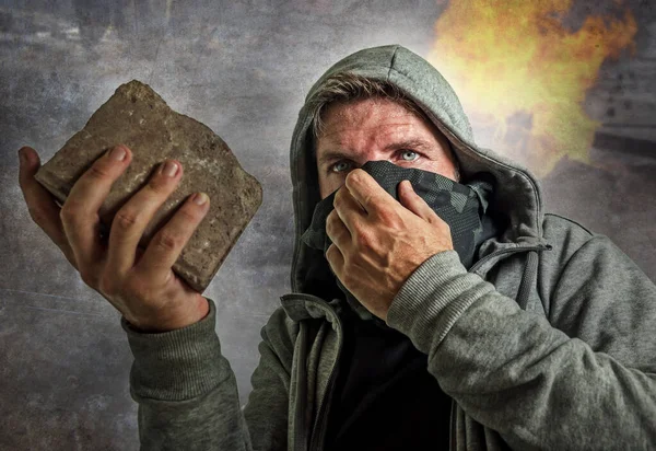 Ung man som ultra och radikal anarkist upplopp. rasande antifa protestant i ansiktet mask kasta tegel fientlig på gatan på demonstration i violett upplopp och kaos — Stockfoto