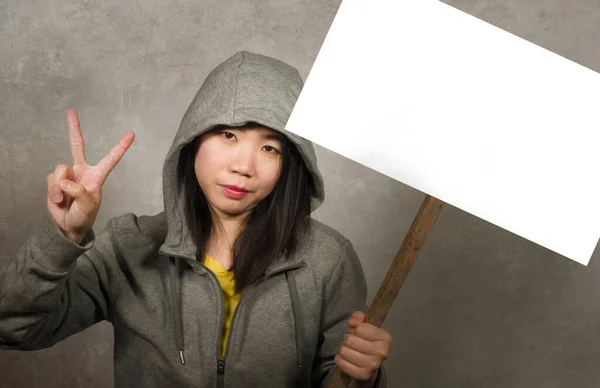 Νεαρή όμορφη Ασιάτισσα φοιτήτρια από την Κορέα ως διαδηλώτρια και ειρηνίστρια κρατώντας διαφημιστική πινακίδα διαμαρτυρίας με κενό χώρο αντιγραφής που στέκεται ενάντια στη βία κάνοντας τα δάχτυλα σύμβολο ειρήνης — Φωτογραφία Αρχείου