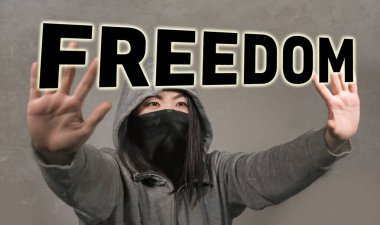 Yüz maskeli genç Asyalı kadın özgürlük sözcüğünün arkasında el kaldırıyor barış ve insan hakları için parlıyor ayrımcılığa ve şiddete karşı