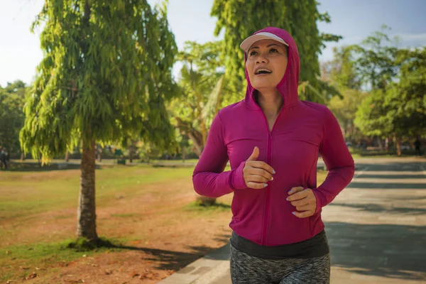 Atraente senhora de meia idade correndo feliz no parque da cidade. mulher bonita e desportiva em seus 40 anos exercitando-se fazendo jogging treino em uma manhã ensolarada desfrutando de um estilo de vida saudável — Fotografia de Stock
