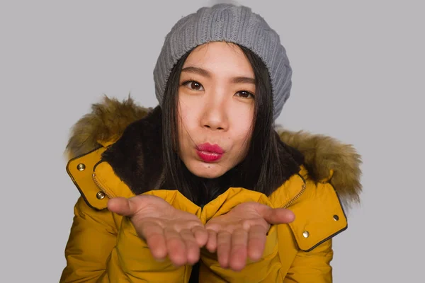 Moda isolado retrato de jovem bonita e feliz mulher coreana asiática no chapéu de inverno e casaco de penas amarelo quente com capuz de pele gesticulando alegre e brincalhão sorrindo — Fotografia de Stock