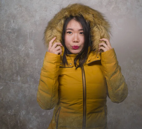 Winter fashion isolated portrait of young beautiful and happy Asian Chinese woman in warm yellow feather jacket with fur hood gesturing cheerful and playful smiling — Stock Photo, Image