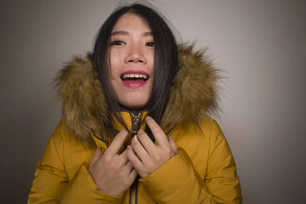 Зимняя мода изолированный портрет молодой красивой и счастливой азиатской кореянки в теплой желтой перьевой куртке с меховым капюшоном жестом веселой и игривой улыбкой — стоковое фото