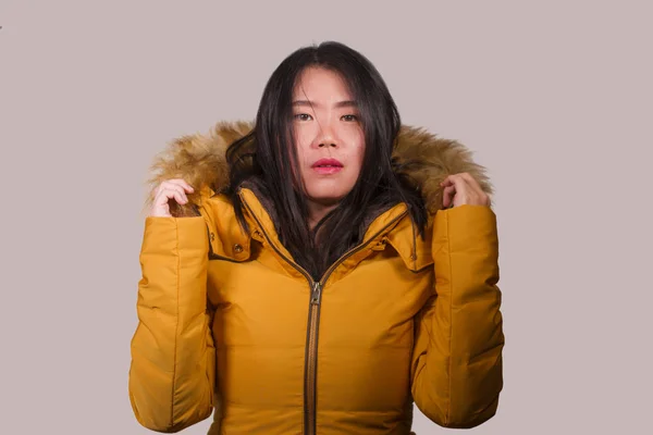 Genç, güzel ve havalı Asyalı Japon kadın kış havasında poz veriyor. Stüdyo arka planında kürk kapüşonlu sarı ceket giyiyor. — Stok fotoğraf