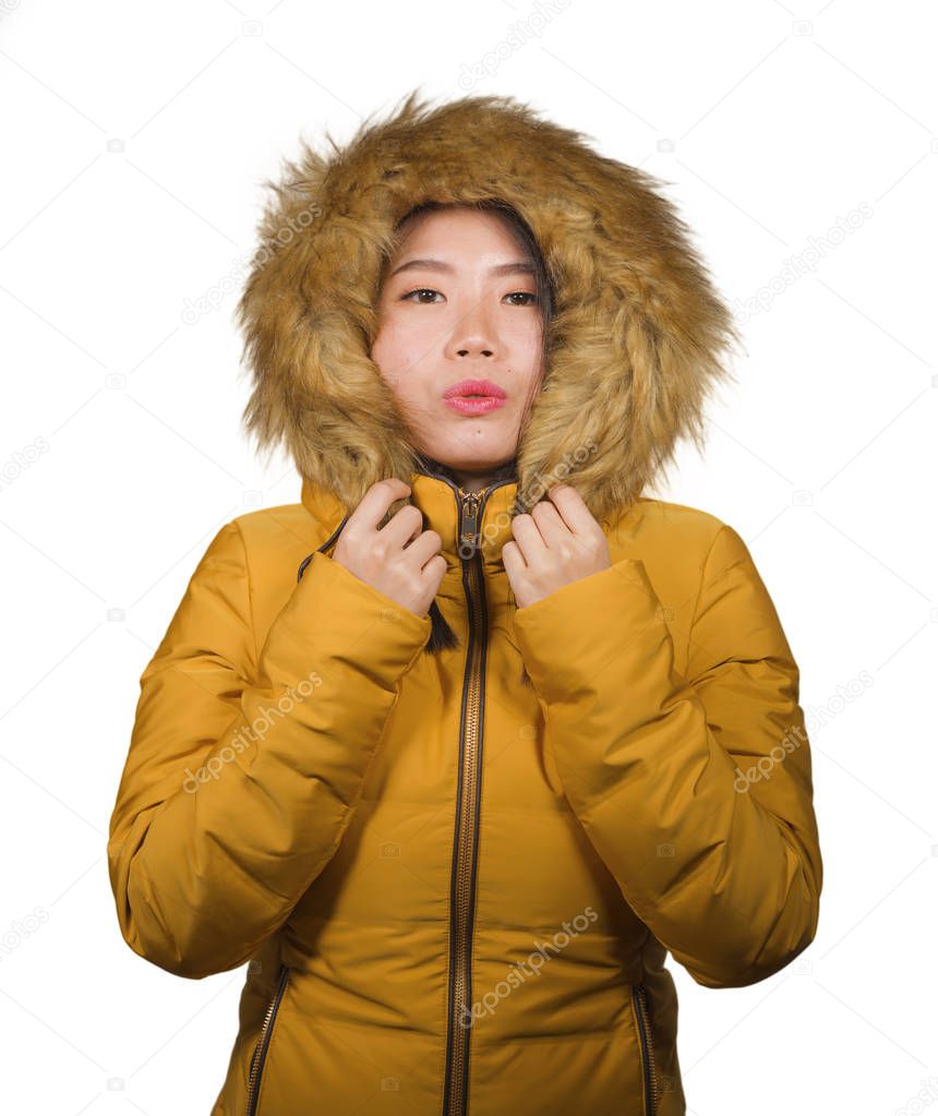 young beautiful and cool Asian Japanese woman posing in Winter weather wearing yellow jacket with fur hood isolated on studio background