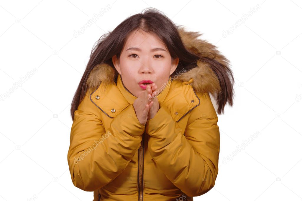 young beautiful Asian Korean woman feeling cold and chilly freezing feeling cold in Winter weather wearing yellow jacket with fur hood isolated on white studio background