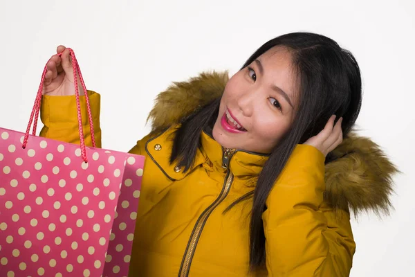 Joven hermosa y feliz asiática coreana mujer en fresco invierno chaqueta celebración bolsa de compras emocionada compra regalo de Navidad sonriente alegre en la moda y belleza concepto aislado — Foto de Stock