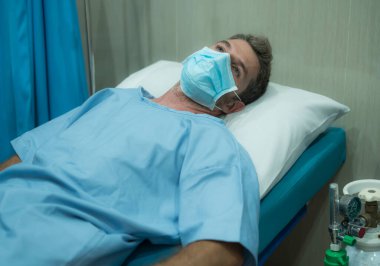 Çekici ve korkmuş bir adam kovid 19 'dan etkilenmiş. Yüz maskesi takmış yetişkin bir erkeğin dramatik portresi hastanede tedavi görüyor. Solunum hastalığından muzdarip. 