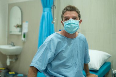 Çekici ve korkmuş bir adam kovid 19 'dan etkilenmiş. Yüz maskeli yetişkin bir erkeğin dramatik portresi hastanede tedavi görüyor. Solunum hastalığından muzdarip. 