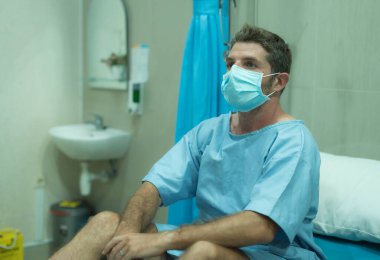 Çekici ve korkmuş bir adam kovid 19 'dan etkilenmiş. Yüz maskeli yetişkin bir erkeğin dramatik portresi hastanede tedavi görüyor. Solunum hastalığından muzdarip. 