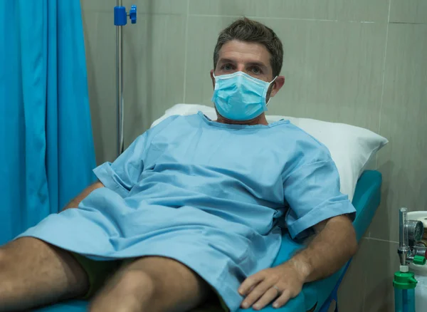 受Covid 19感染的有吸引力又害怕的男人 一副戴口罩的成年男性在医院里接受治疗的戏剧性画像 他躺在床上忧心忡忡 — 图库照片