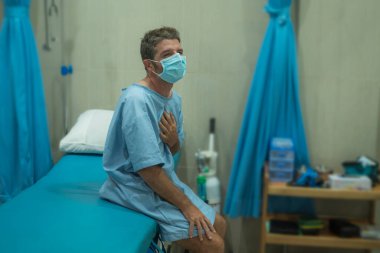 Çekici ve korkmuş bir adam kovid 19 'dan etkilenmiş. Yüz maskeli yetişkin bir erkeğin dramatik portresi hastanede tedavi görüyor. Solunum hastalığından muzdarip. 