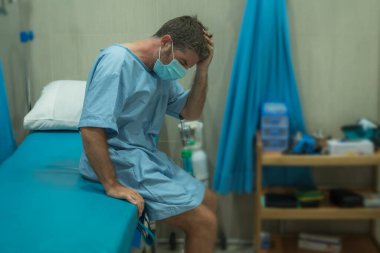 Çekici ve korkmuş bir adam kovid 19 'dan etkilenmiş. Yüz maskeli yetişkin bir erkeğin dramatik portresi hastanede tedavi görüyor. Solunum hastalığından muzdarip. 