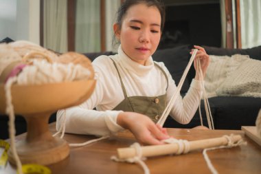 Makrome el sanatları hobisini seven Asyalı bir kız. Genç mutlu ve güzel Çinli evde makrome yapıyor. Ev yapımı el yapımı ipler, ipler ve iplikler kullanıyor.