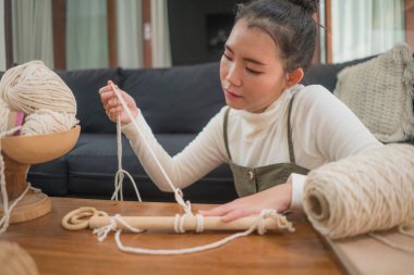 Makrome el sanatları hobisinden hoşlanan Asyalı bir kız. Genç, mutlu ve güzel bir Koreli kadın evde makrome yapıyor. Ev yapımı el yapımı ipler, ipler ve iplikler kullanıyor.