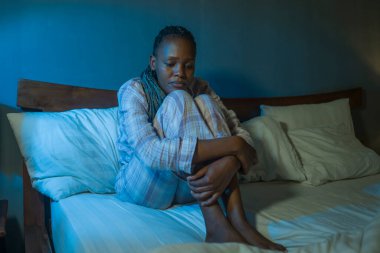 Genç üzgün ve depresif siyah Afro-Amerikan kadın evde yatağında mutsuz ve uykusuz bir şekilde depresyon ve uykusuzluk çekiyor.