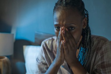 Genç üzgün ve depresif siyah Afro-Amerikan kadın evde yatağında mutsuz ve uykusuz bir şekilde depresyon ve uykusuzluk çekiyor.
