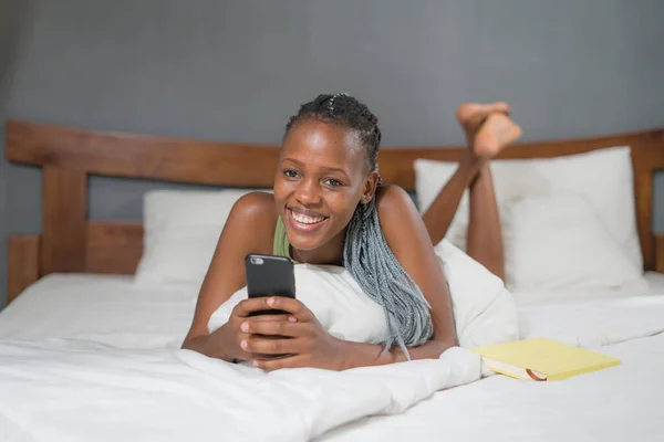 행복하고 매력적 침대에 미디어 사용하여 핸드폰에서 편안하고 즐거운 온라인 데이트를 — 스톡 사진