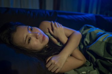 Genç, üzgün ve depresif Asyalı bir kadının dramatik ev hayatı portresi. Acı içinde uzanmış, kanepede ağlıyor. Stresli ve endişeli depresyonda. 